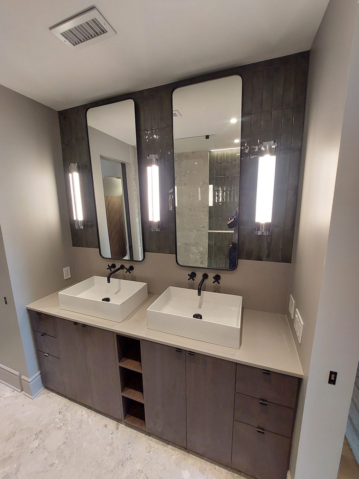 Double vanity with vessel sinks, dark tile feature wall and black wall-mounted faucets